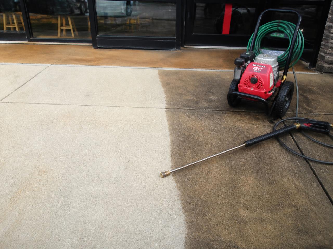 Pressure washer cutting a clean stripe across a commercial sidewalk