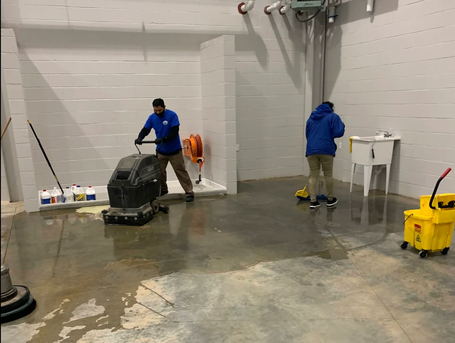 Walk-behind floor scrubber running across an industrial floor